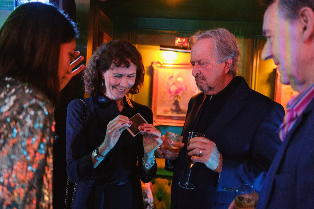 Candid moment of guests reacting to a magician’s trick at a Mayfair birthday party