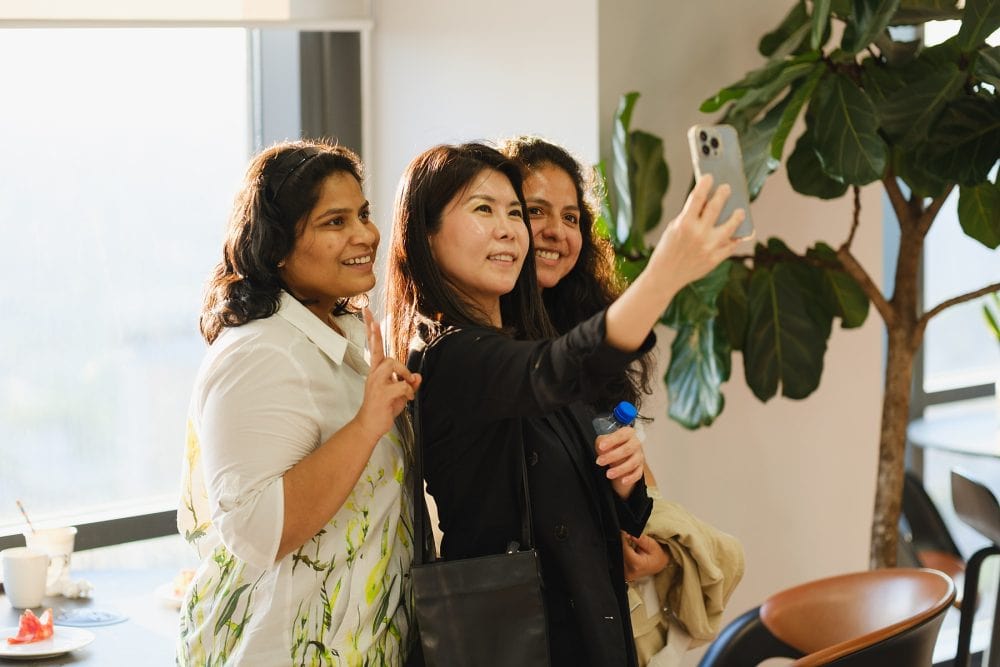 Attendees taking selfie together at a fintech event on the 39th floor of One Canada Square