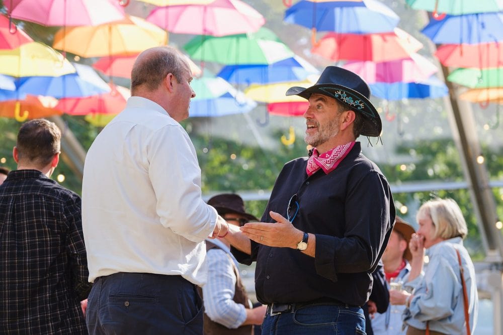 Guests laughing and enjoying drinks during summer party on the covered decking