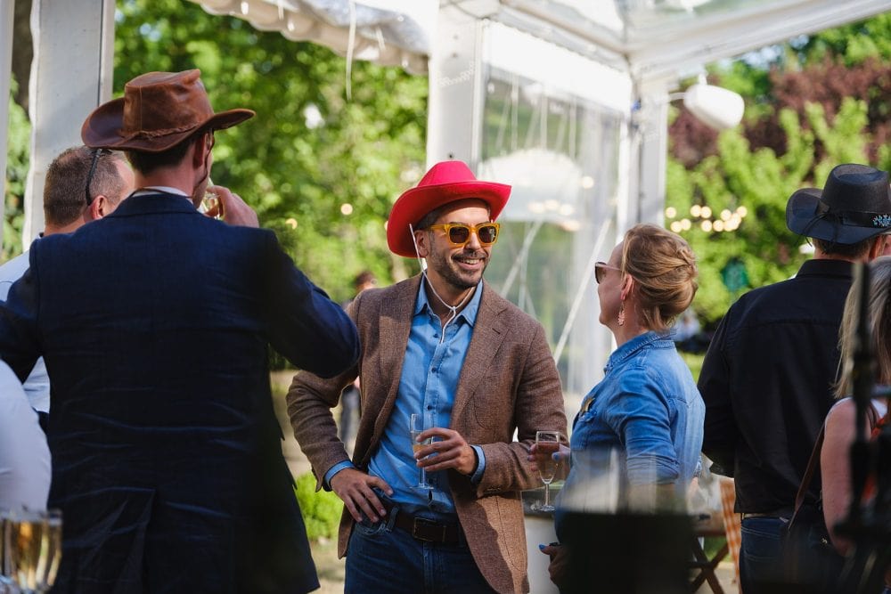 Guests laughing and enjoying drinks during summer party outside the marquee