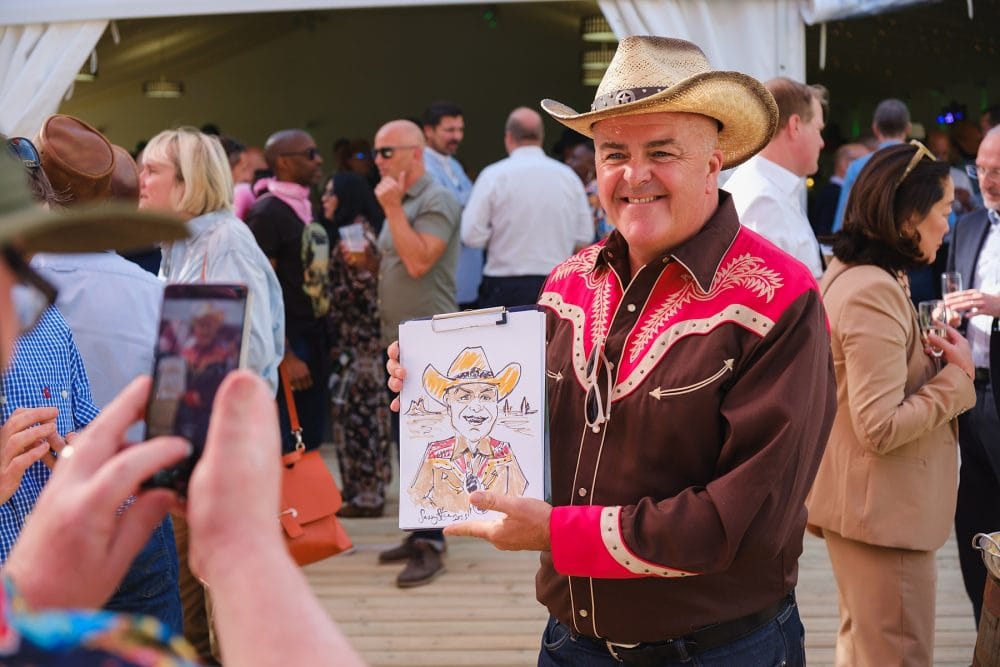 guest posing with their caricature at Regent’s University summer party