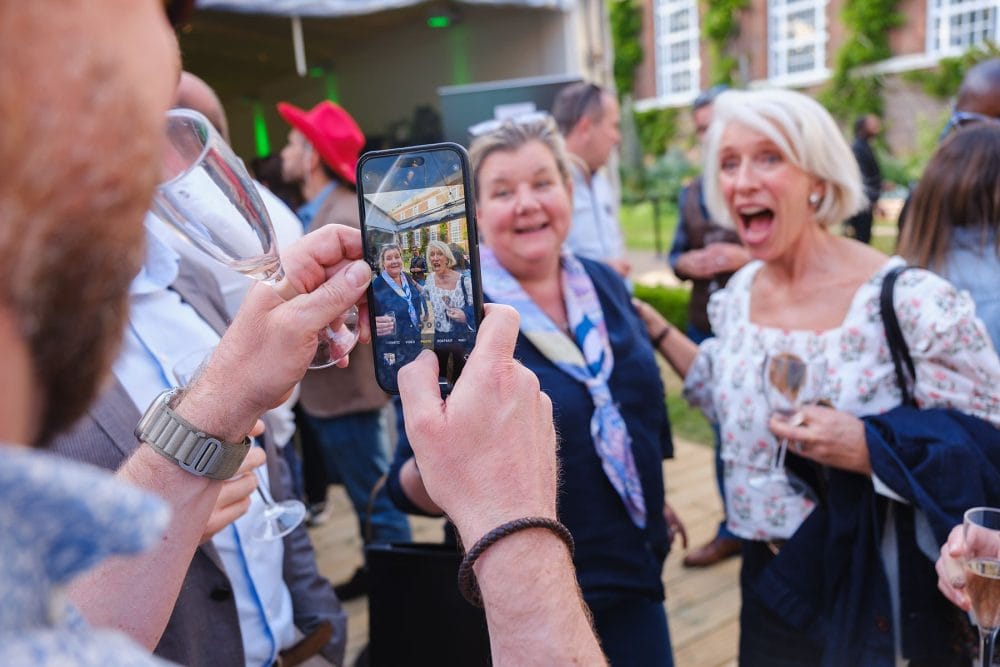 Guests laughing and enjoying drinks during summer party on the lawns