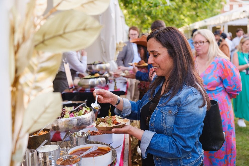 Food stalls in service at summer party with guests ordering meals