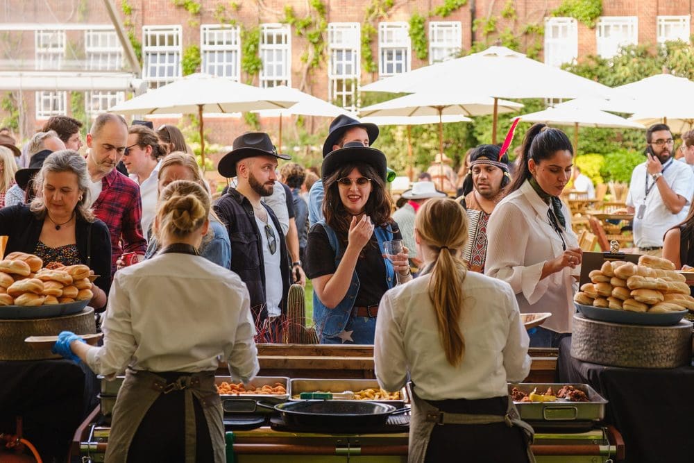Food stalls in service at summer party with guests ordering meals
