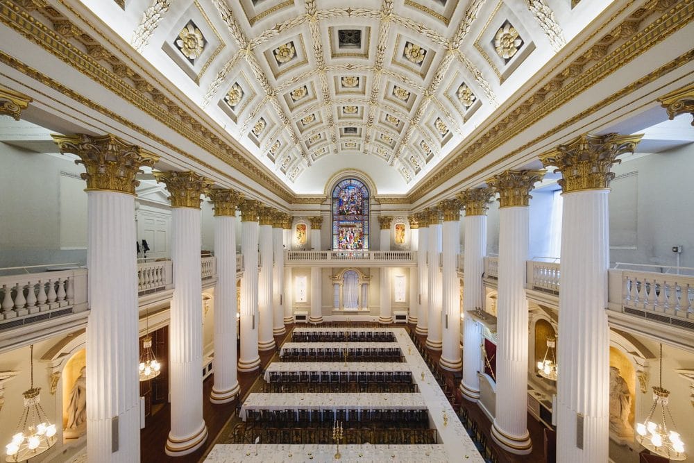Wide shot of the Egyptian Hall at Mansion House from balcony level, set up for an anniversary dinner