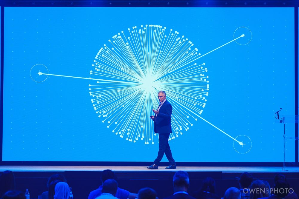 Speaker presenting against high-resolution LED screens at Vision Hall