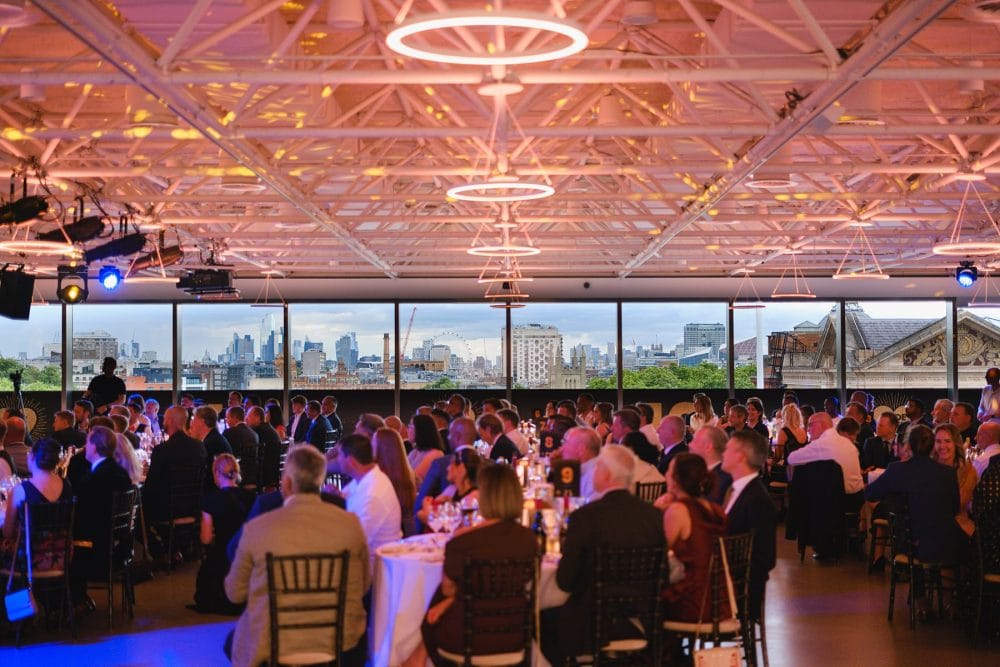 wide shot of guests seated for dinner with panoramic views over London, in Illuminate at the Science Museum